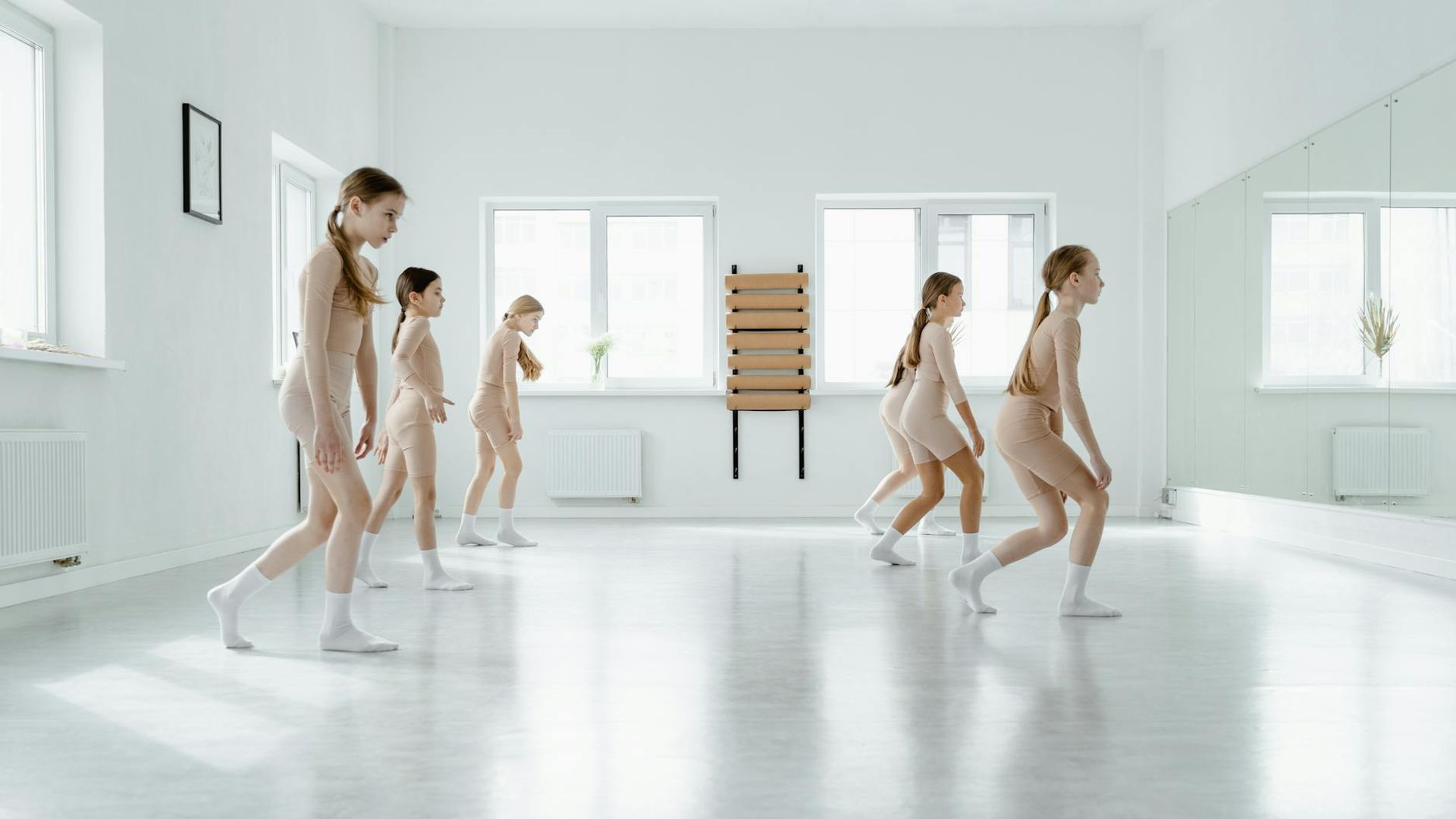 Woman practicing gentle movements in a sunlit minimal studio